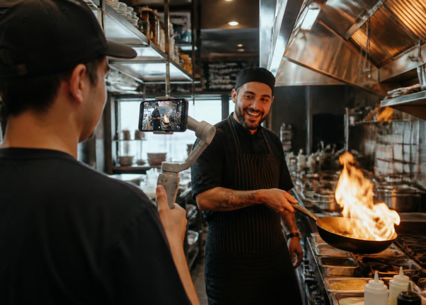 A creator filming a chef in a restaurant kitchen